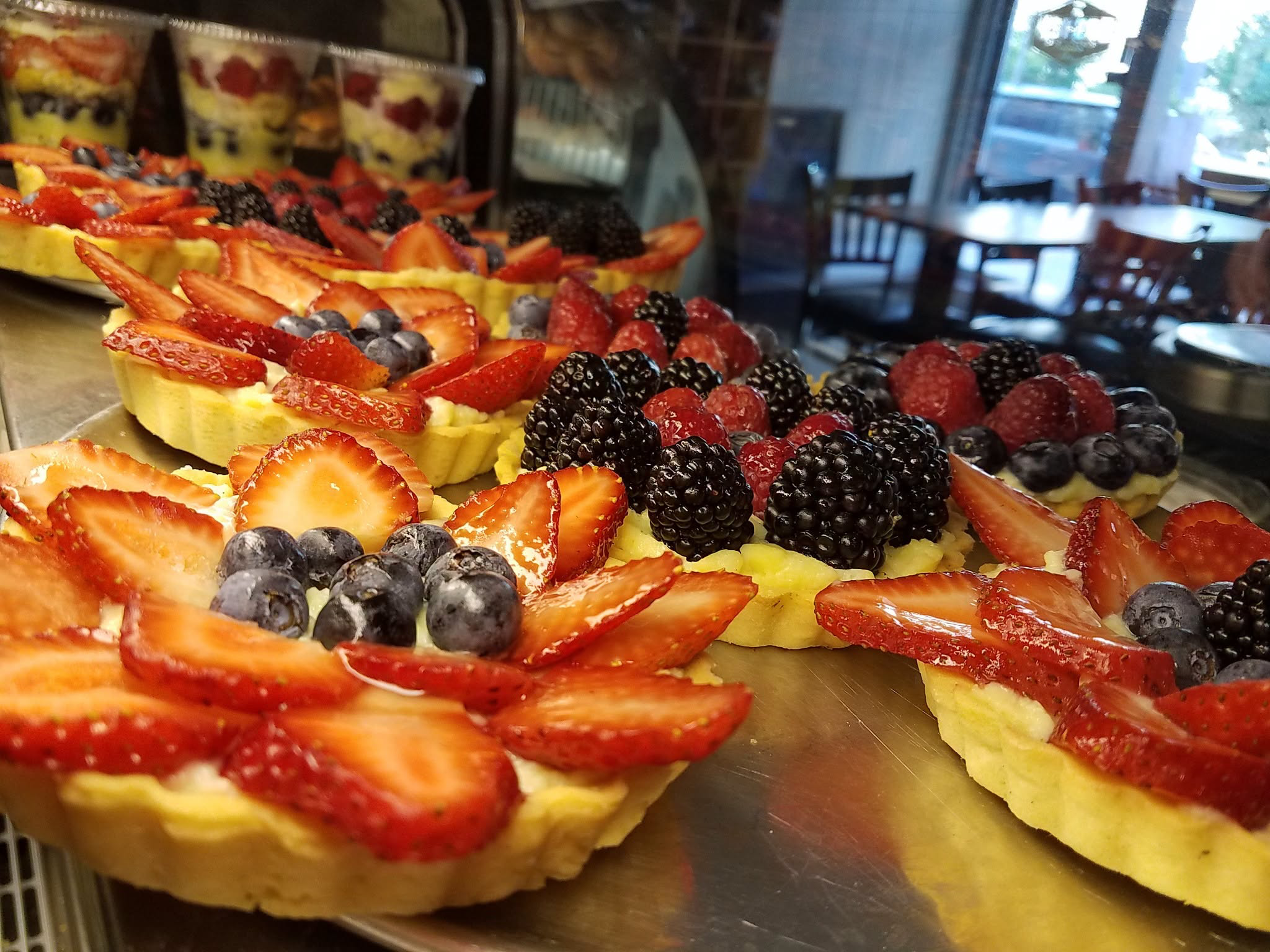 Fruit tarts in the bakery display case with afternoon light