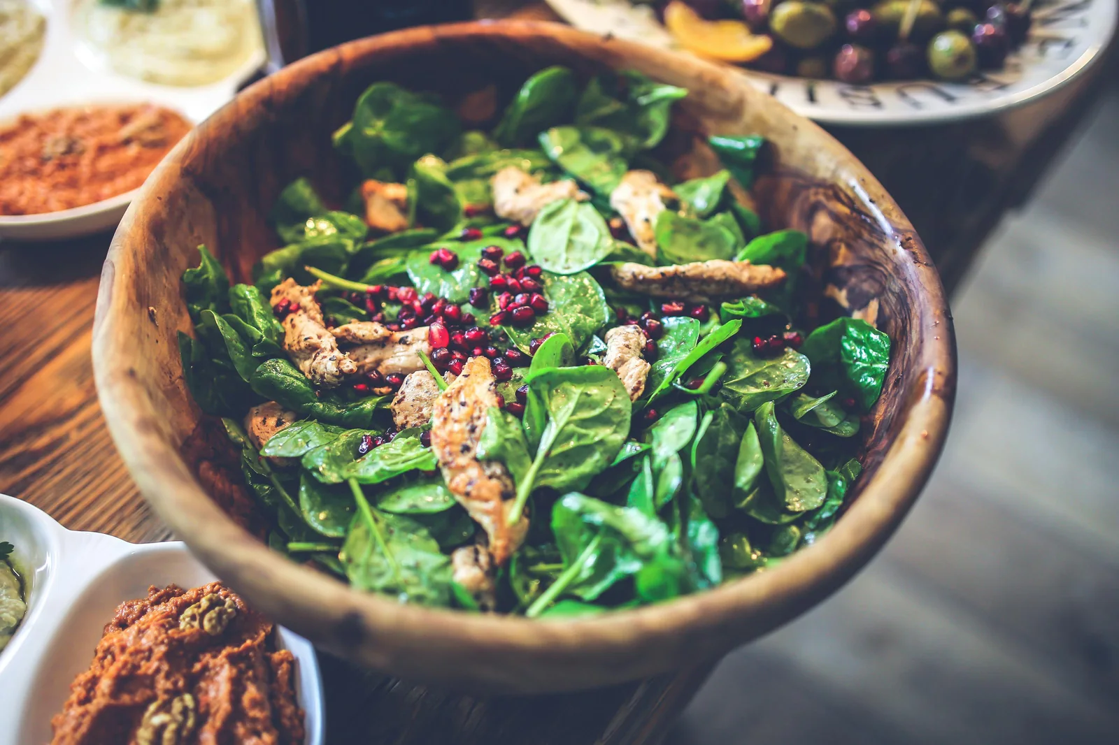 A spinach salad with berries, almonds, and bleu cheese in a wooden bowl