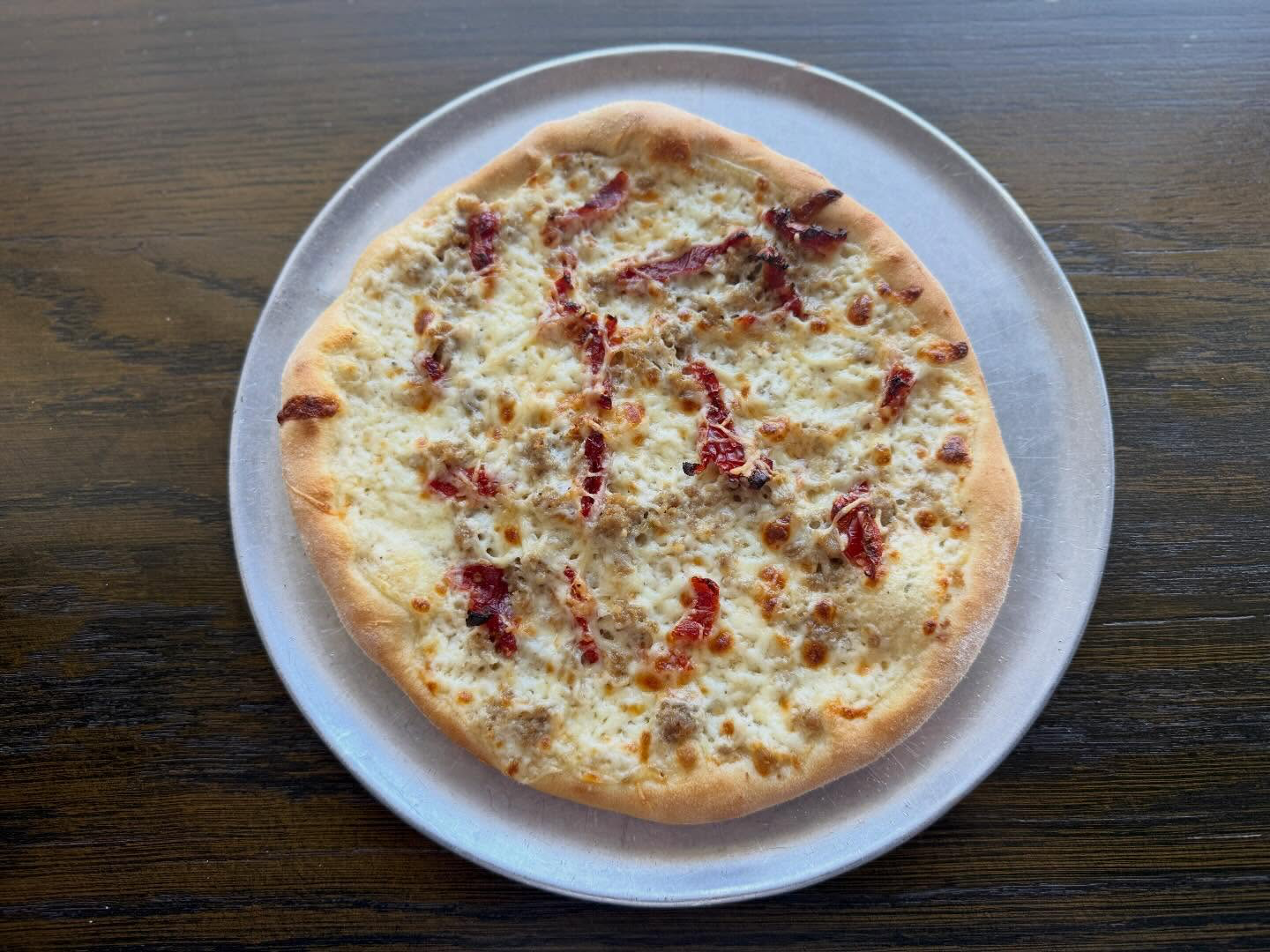 White pizza with sun-dried tomatoes on a metal tray