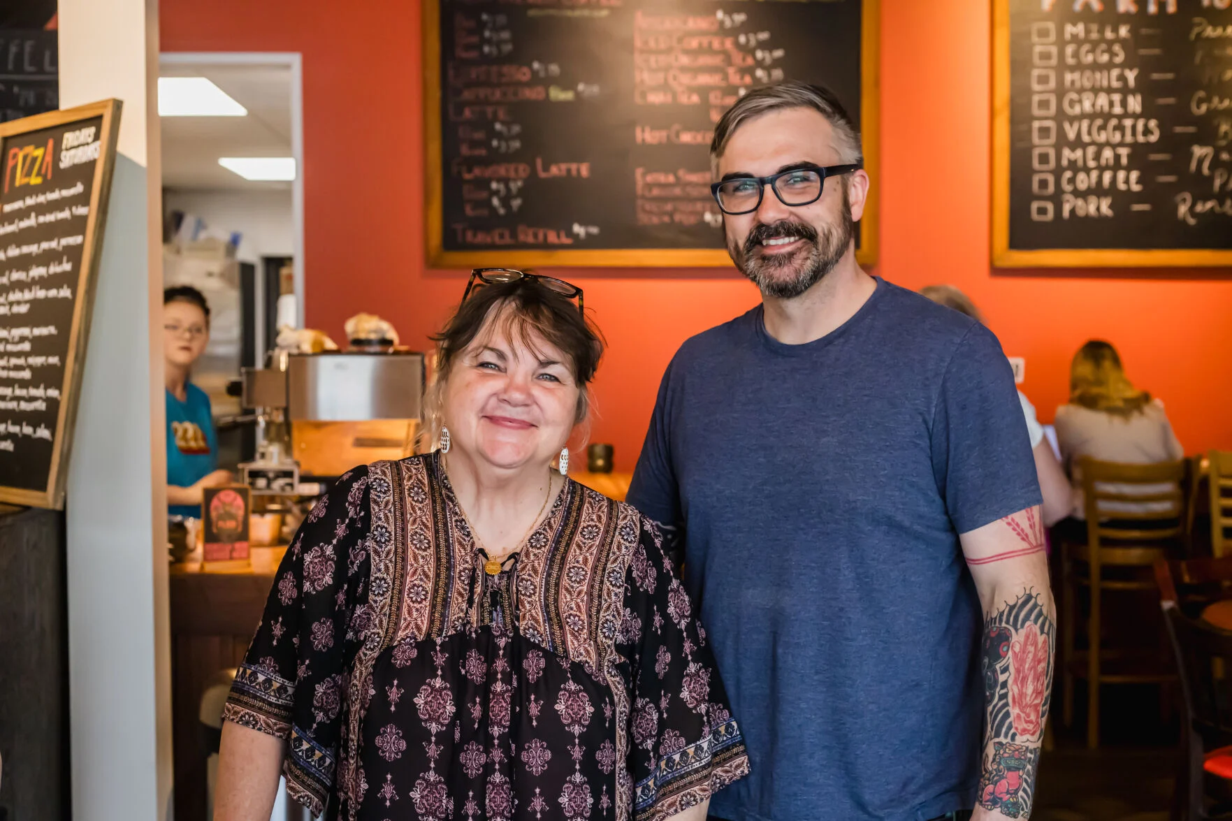 Trevor and Kim together in front of the chalkboard menu wall at 222 Artisan Bakery