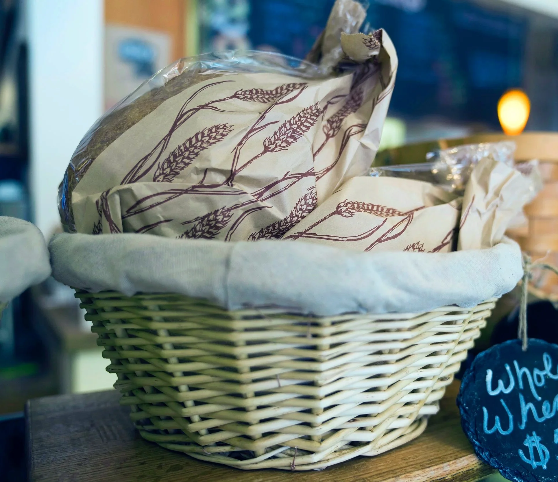A wicker basket of whole wheat loaves wrapped in printed paper